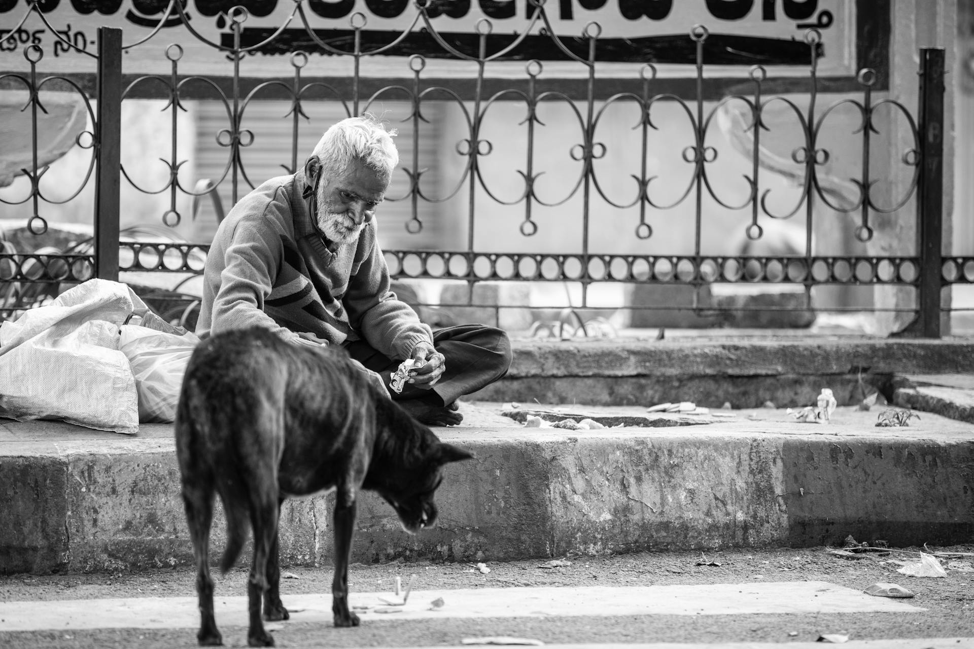 Gråskalat foto av en äldre man som matar en hund