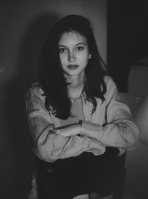 Free Black and white portrait of a caucasian woman sitting with arms crossed, looking directly at the camera. Stock Photo