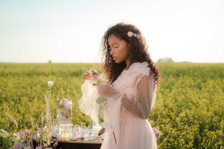 Woman In Tulle Dress Standing In Flower Field Next To Glass Laboratory Equipment