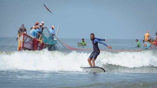 Photo of a Man Surfing Near a Boat