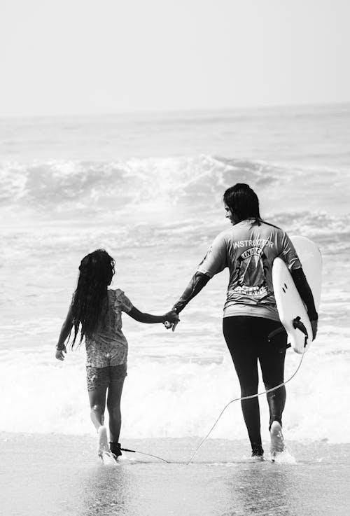 Free Back View of a Woman and a Kid Walking while Holding Hands Stock Photo