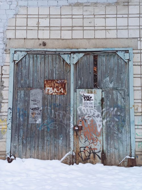 Free Old wooden door with graffiti surrounded by snow in Berdsk, Russia. Stock Photo