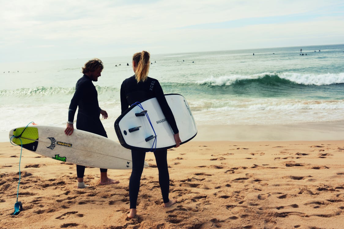 Homme Et Femme Tenant Des Planches De Surf Au Bord De La Mer