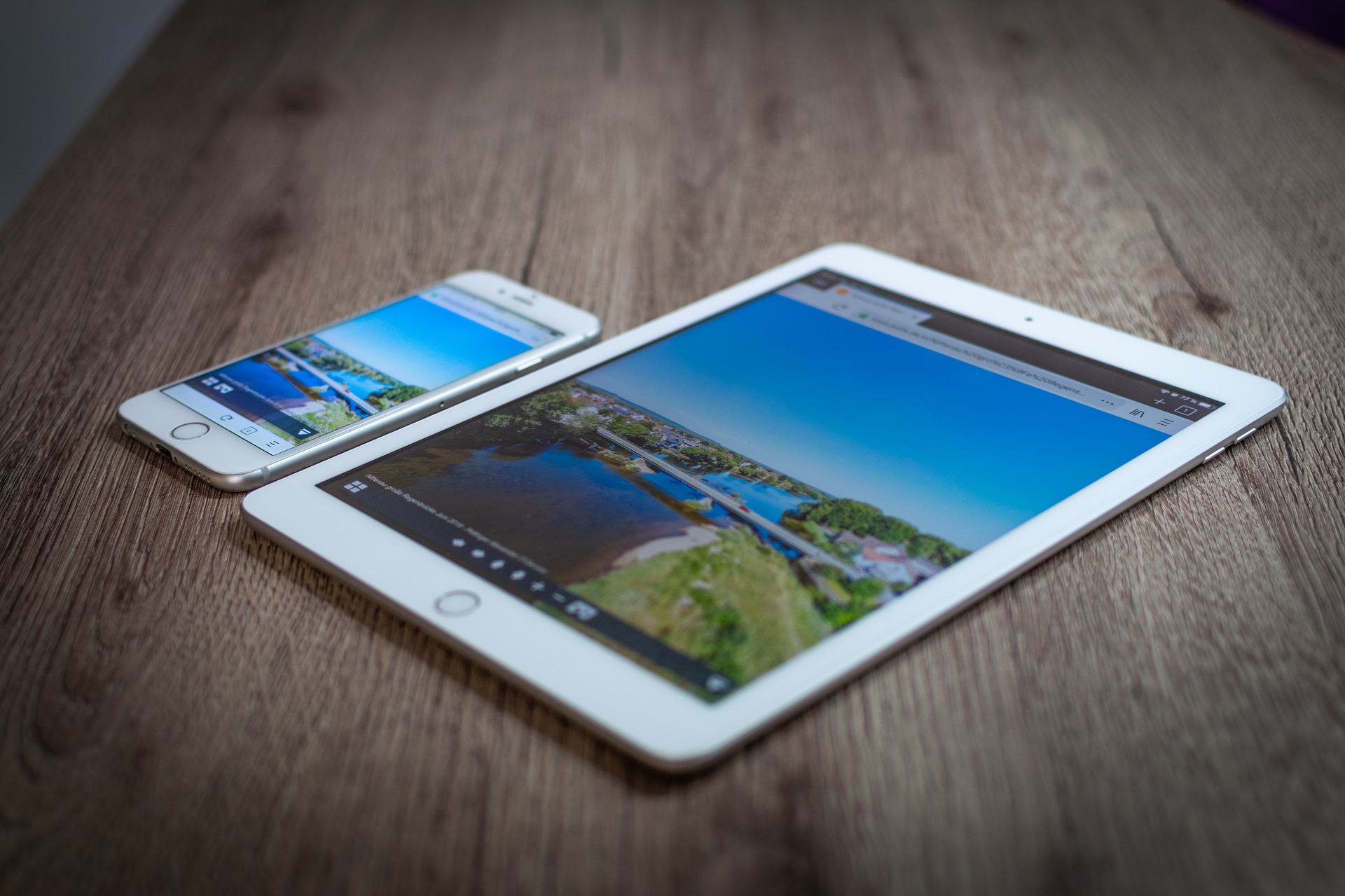 iPad and iPhone showing a scenic landscape on a wooden table, highlighting portability and technology.