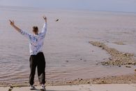 Woman in White Long Sleeve Shirt and Black Pants Standing on Beach