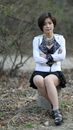 Woman in White Long Sleeve Shirt and Black Skirt Sitting on Brown Rock