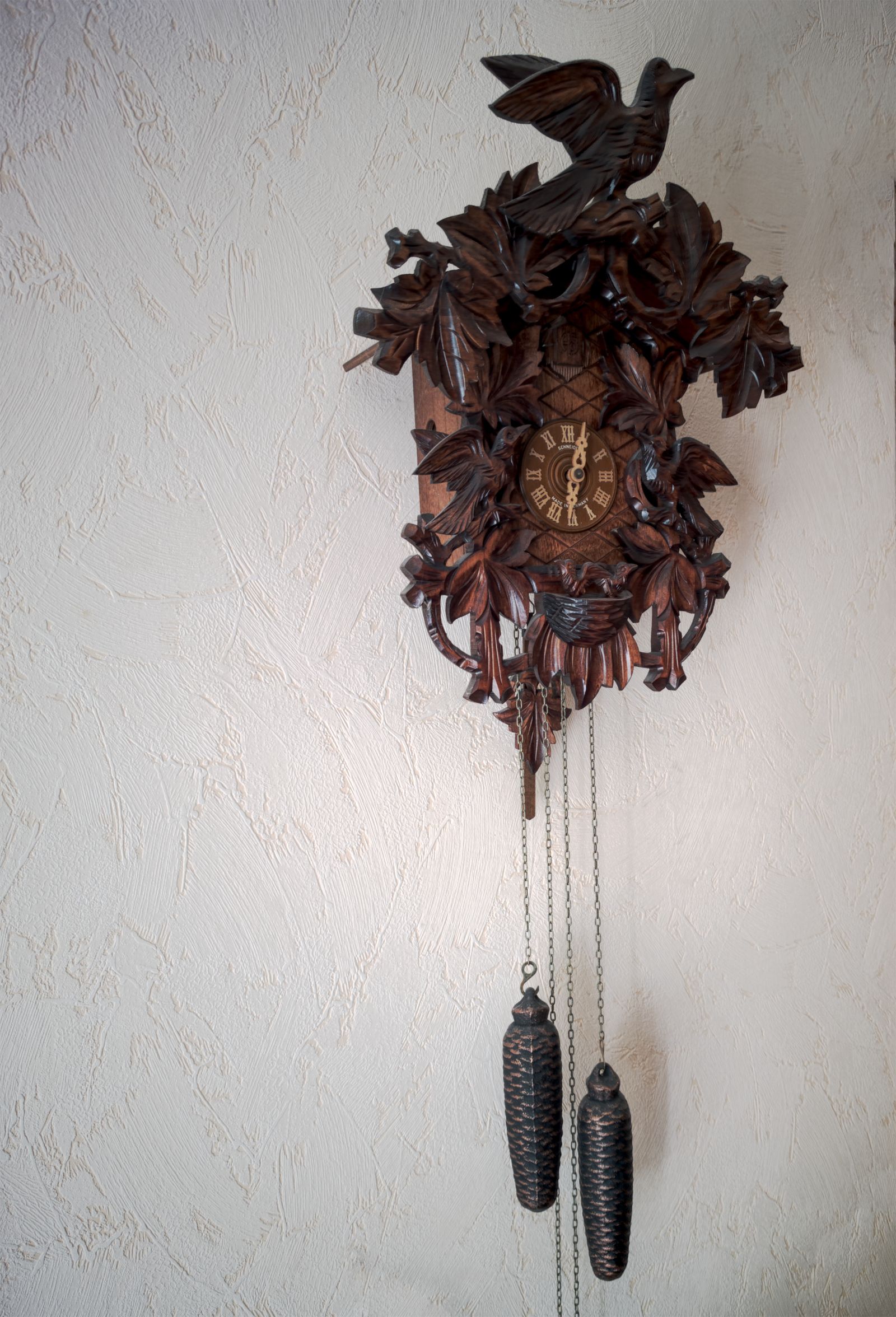 Coucou en bois sculpté orné d'un oiseau avec ses poids en pomme de pin