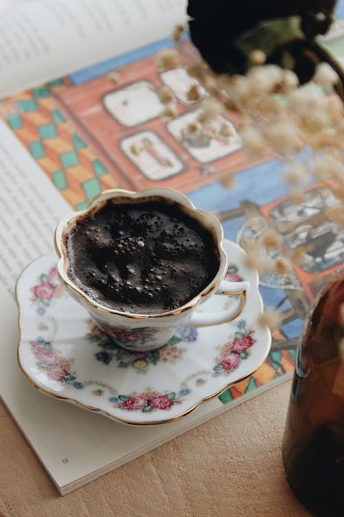 A Floral Teacup with Black Coffee with Bubbles