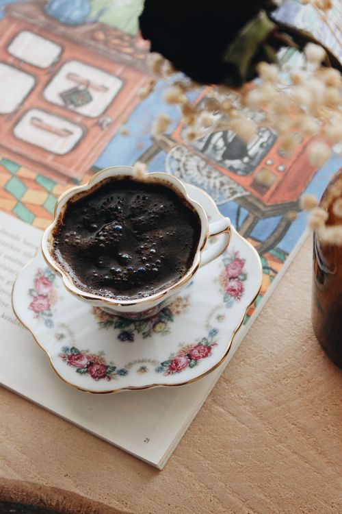 Free A floral-patterned cup of rich coffee elegantly placed on a wooden table indoors. Stock Photo