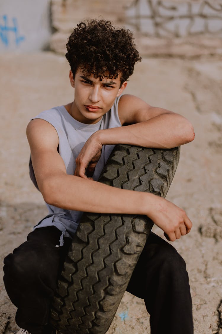 A Boy In Gray Tank Top Sitting Inside The Tire