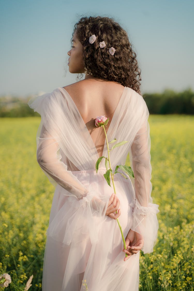 Attractive Woman In Tulle White Dress Holding Rose Behind Back