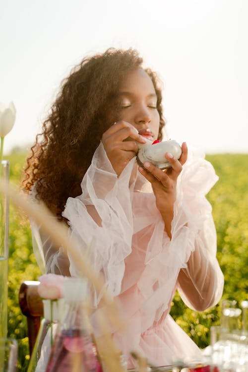 Woman Sitting on a Meadow and Smelling a Flavor