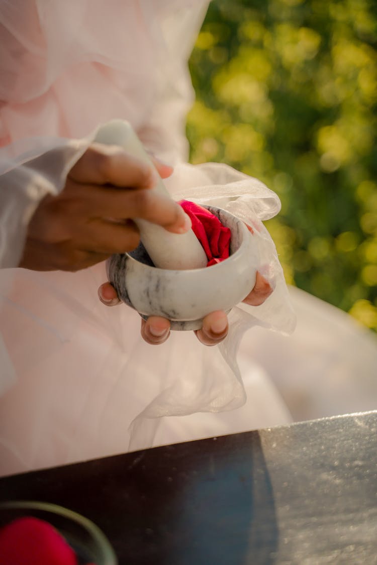 Unrecognizable Hands Beating Red Substance In Mortar With Pestle 