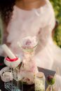 Unrecognizable Woman Sitting at Table with Glass Flask Full of Rose Petals