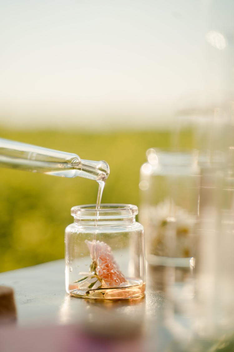 Unrecognizable Person Adding Oil To Flower In Glass Jar