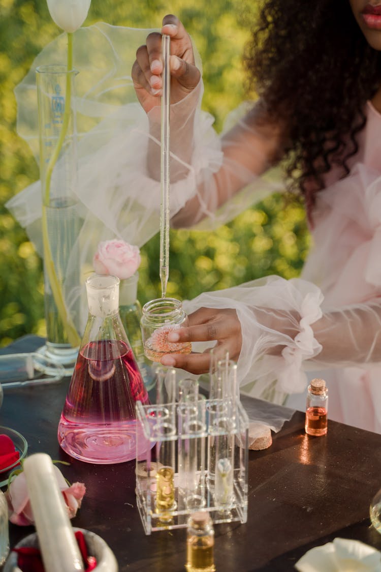 Woman Measuring Some Liquid On A Meadow