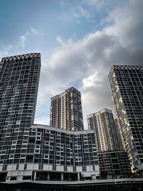 Free Low angle view of modern high-rise buildings with a dramatic cloudy sky background, perfect for real estate and architecture themes. Stock Photo