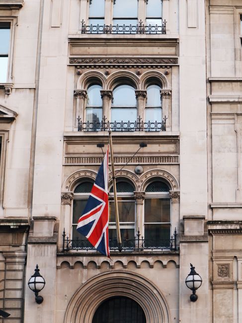 Front view of a historic building with Union Jack flag and arched windows in an urban setting.