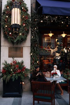 Two women enjoying coffee at a decorated café during the holiday season.