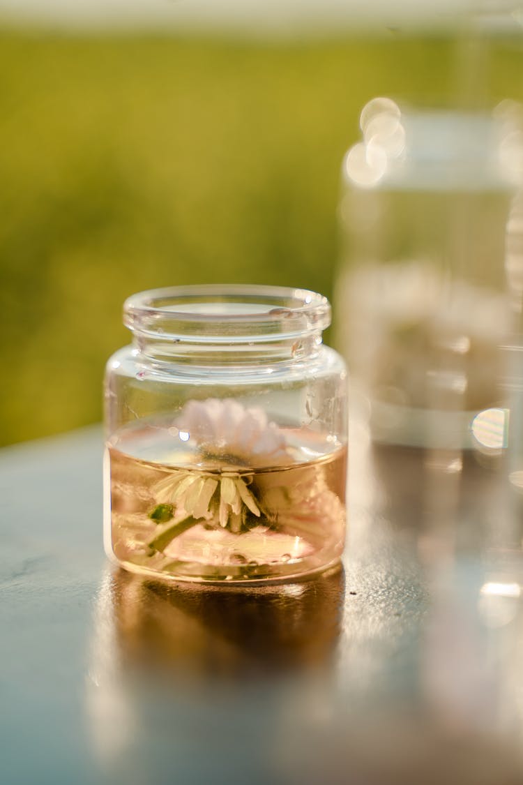 Jar With Flower In Liquid On Table