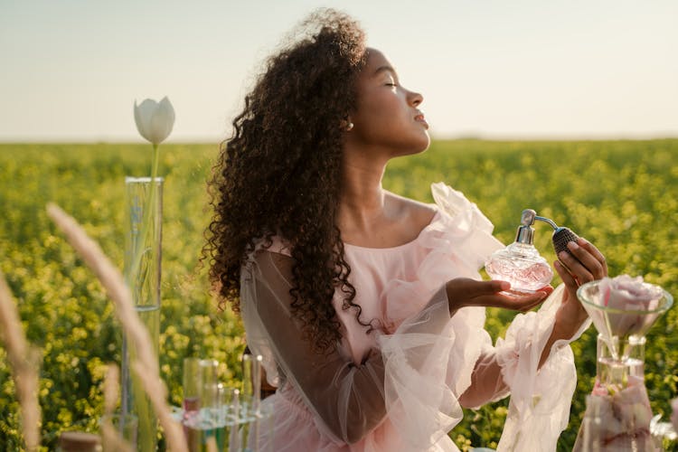 Woman With Perfume Bottle In Flower Field