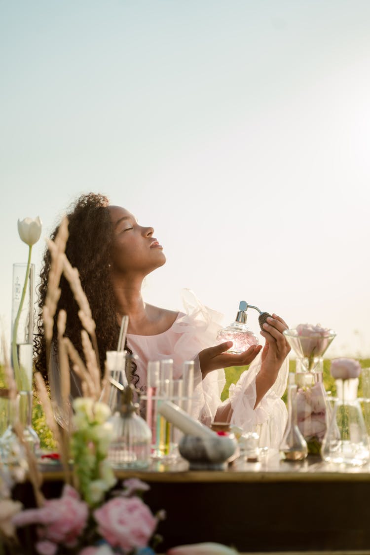 Woman With Perfume Bottle Behind Table