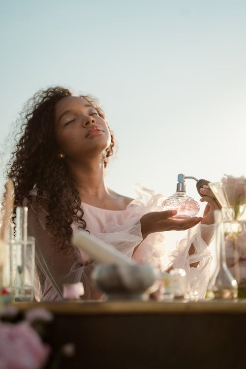 Woman With Perfume Bottle Behind Table