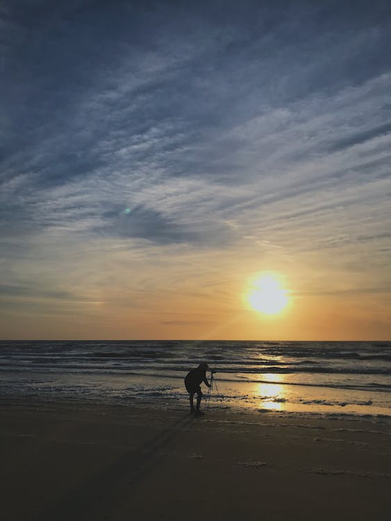무료 해변에 삼각대 스탠드를 배치하는 사람의 실루엣 사진 스톡 사진