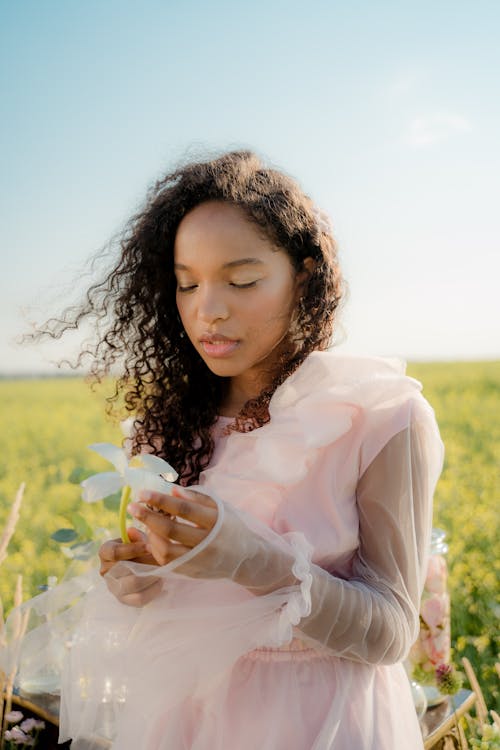 Curly Haired Woman in Dress Holding Flower