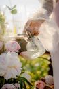 Woman Holding Bottle of Perfume Between Flowers