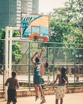 Boys playing basketball outdoors on a sunny day, showcasing athletic action.
