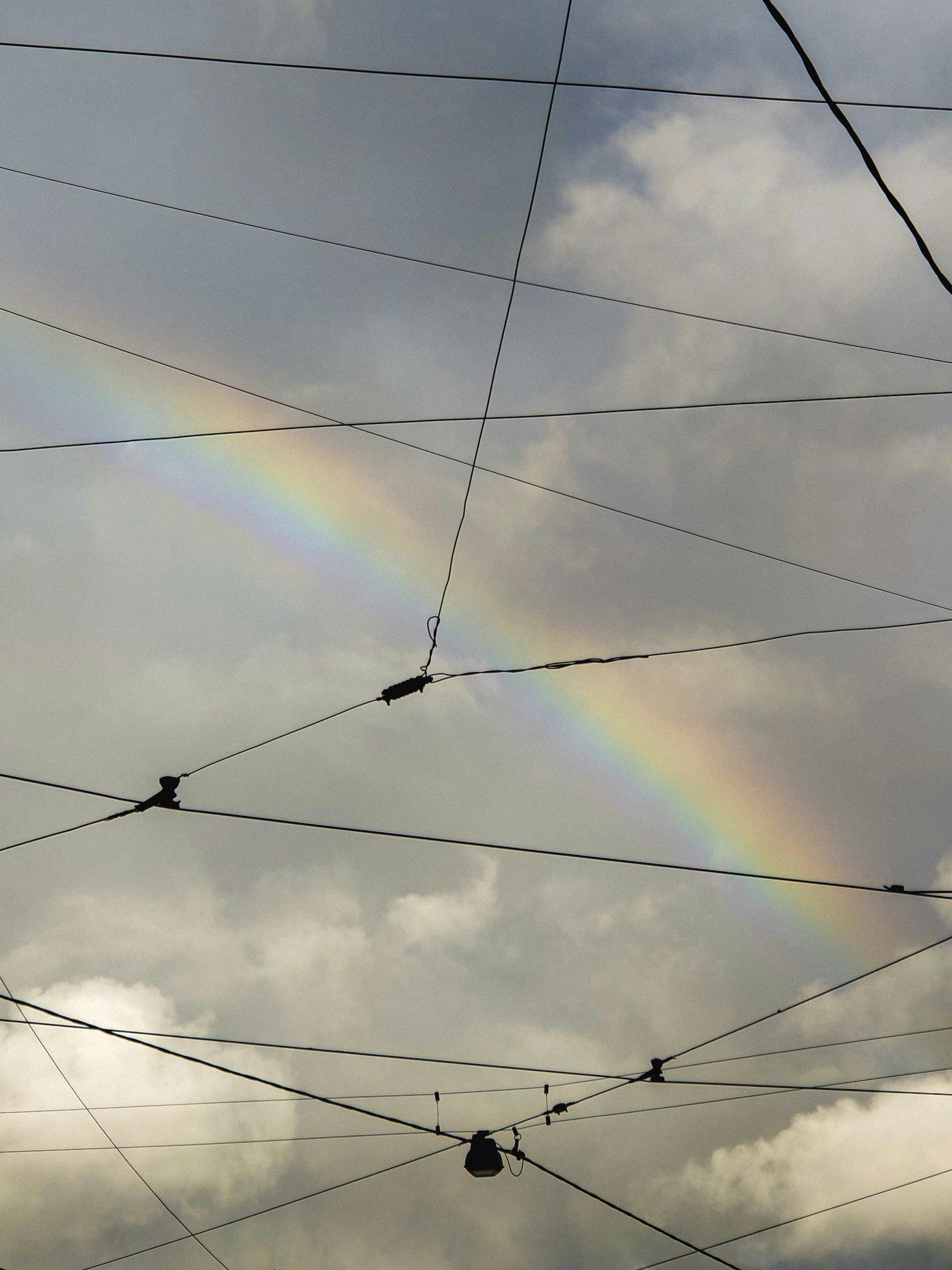 electric wires under white clouds with rainbow