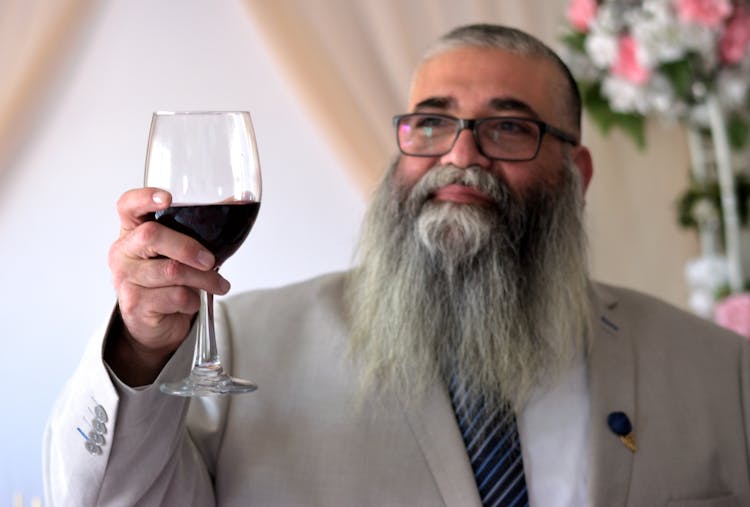 Photo Of An Elderly Man With A Beard Holding A Glass Of Wine