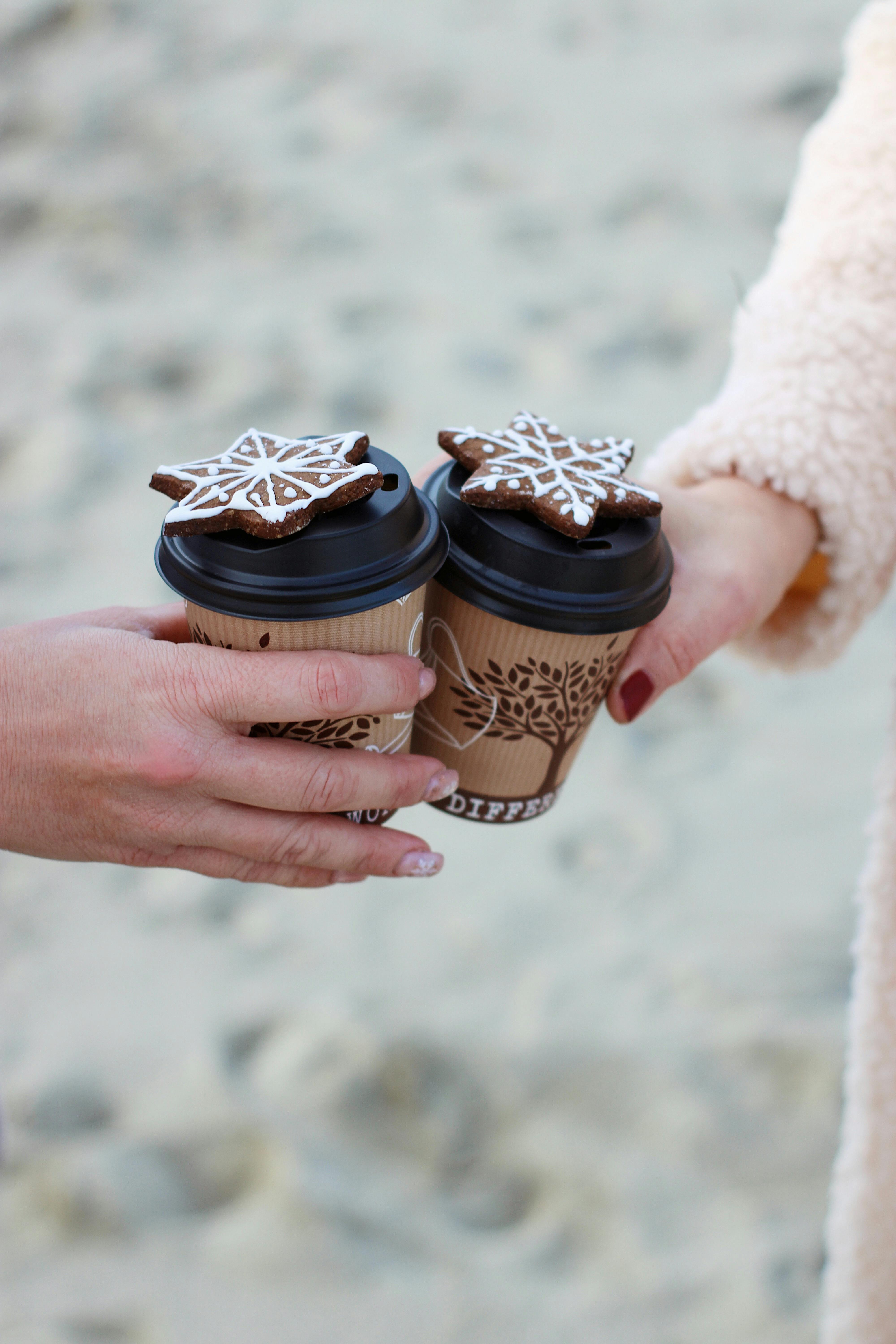 two coffee cups held in hands against white background
