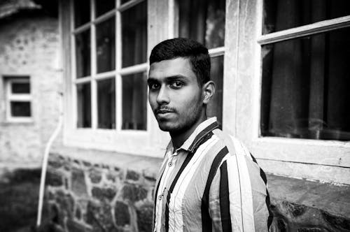 Grayscale Portrait of a Man Near Windows