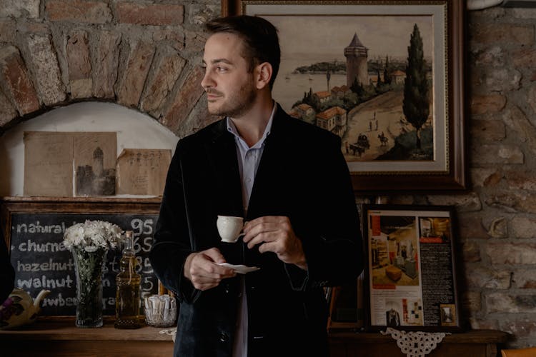 A Man Wearing A Velvet Blazer While Holding A Teacup