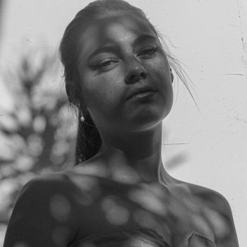 Artistic black and white portrait showcasing shadows and freckles.