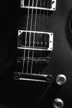 Detailed close-up of electric guitar strings in black and white monochrome style.