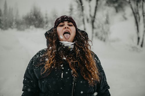 Photo of a Woman with Brown Hair Tasting Snow