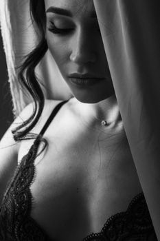 Black and white portrait of a woman in lace lingerie with eyes closed, exuding elegance.