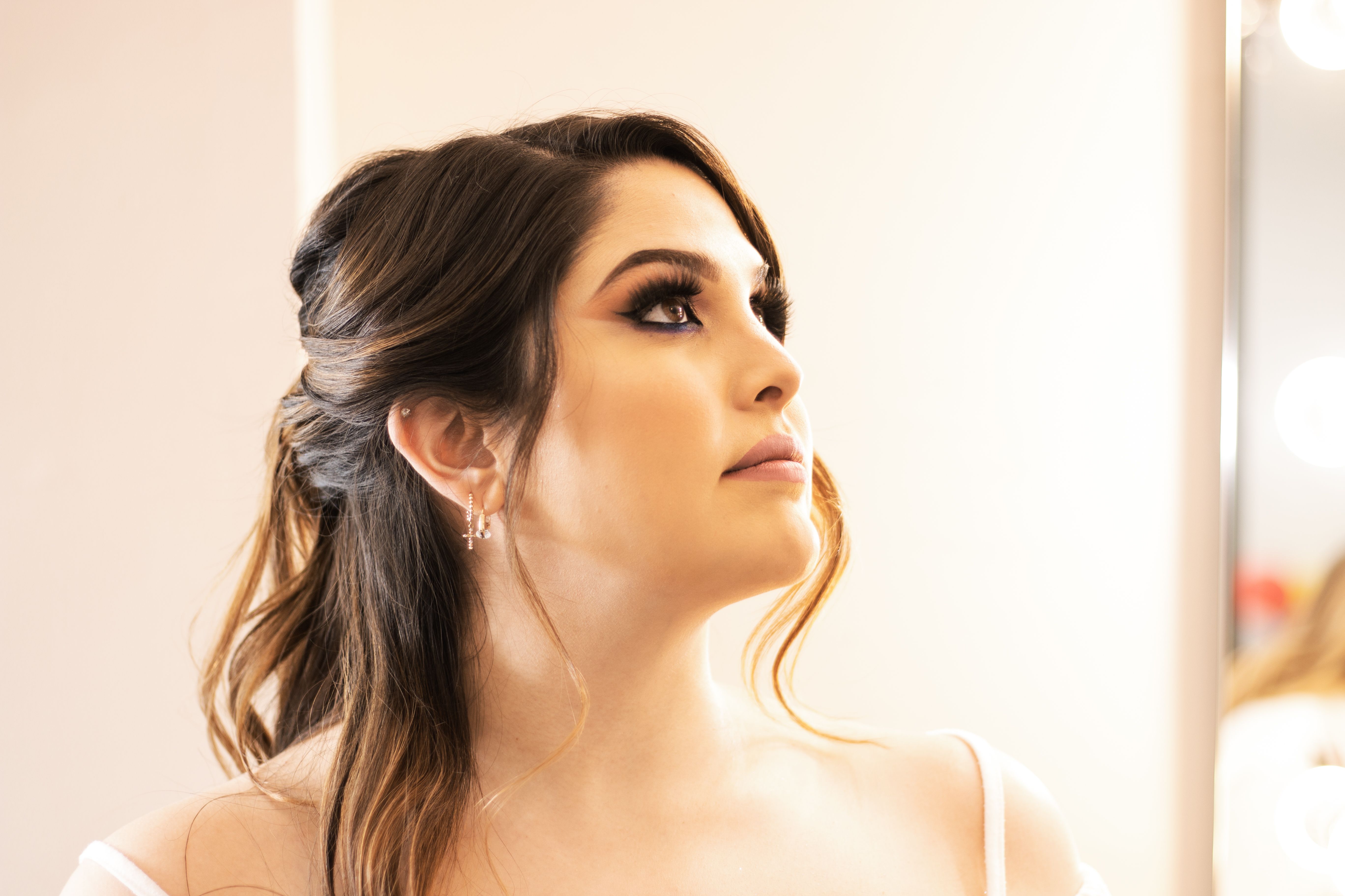 Close-up portrait of a woman with elegant makeup looking up indoors.