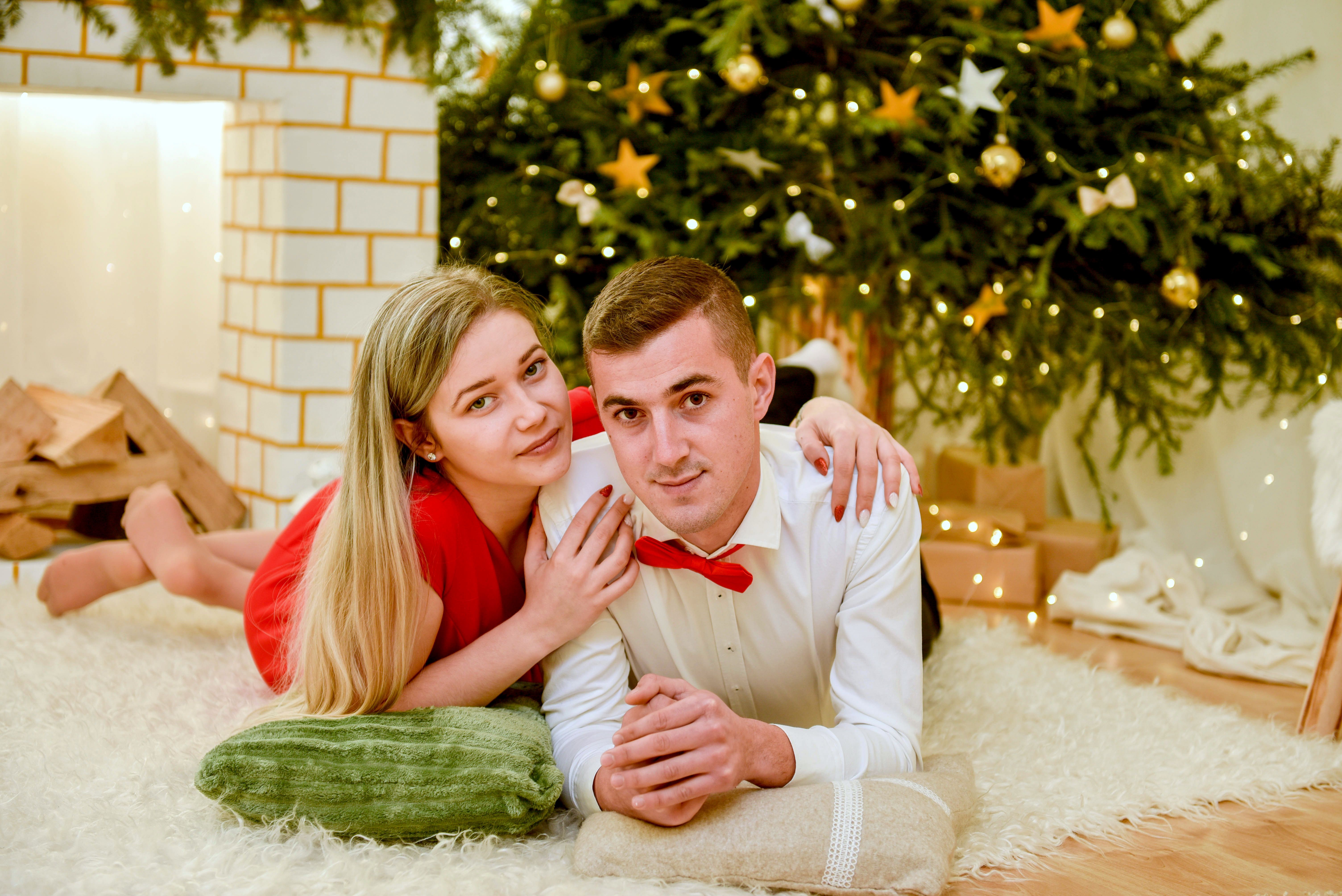 A loving couple poses by a Christmas tree, celebrating the holiday season in style.