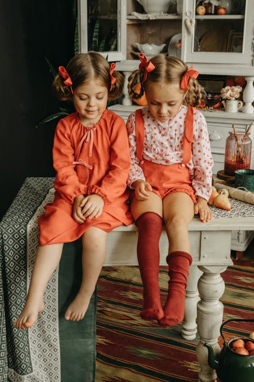 Free Girls with Ribbons in Hair Sitting on Antique Kitchen Table Stock Photo