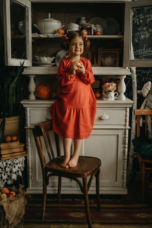 Girl in Red Dress Standing on Chair 