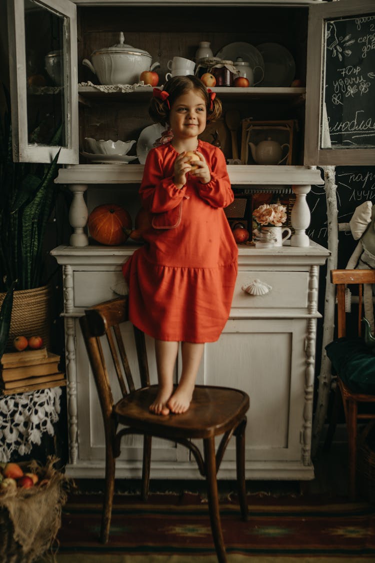 Girl In Red Dress Standing On Chair 