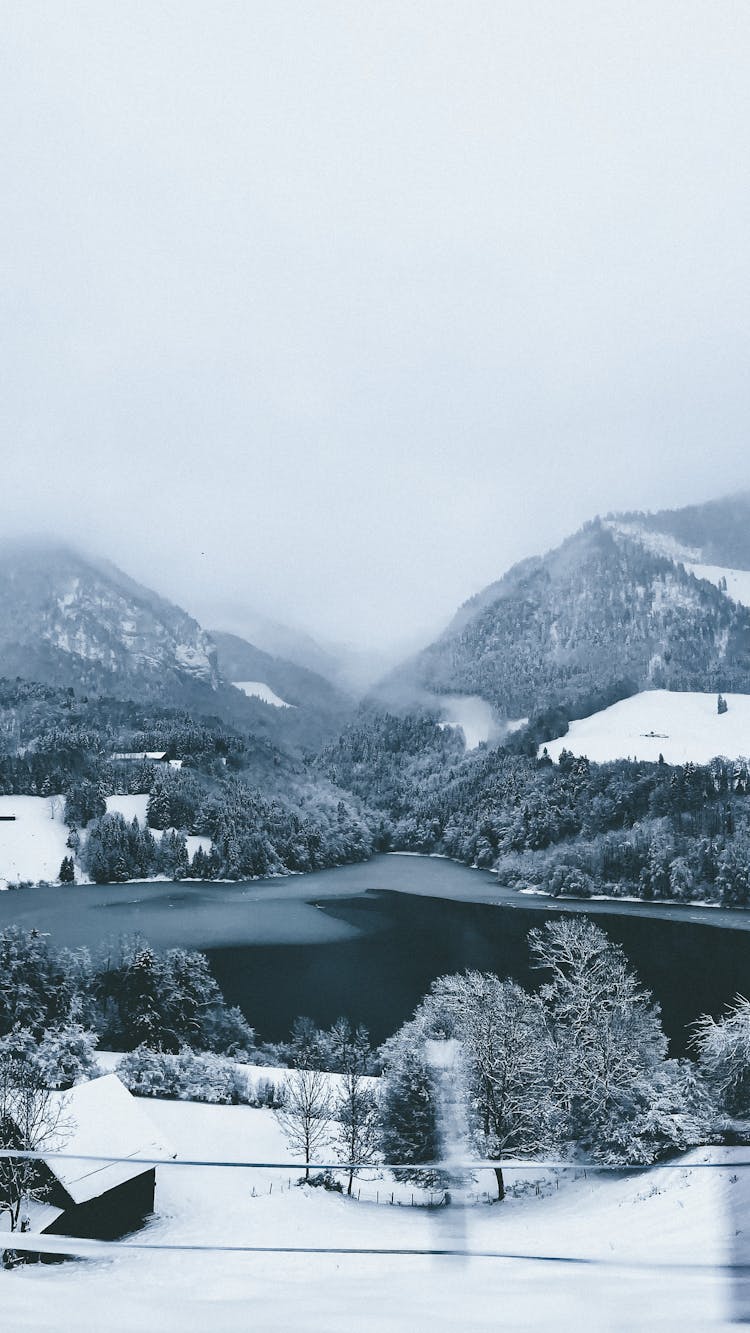View Of An Alpine Lake And A Foggy Valley In Winter
