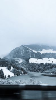 Majestic snow-covered mountains and valley under a cloudy winter sky with icy water.