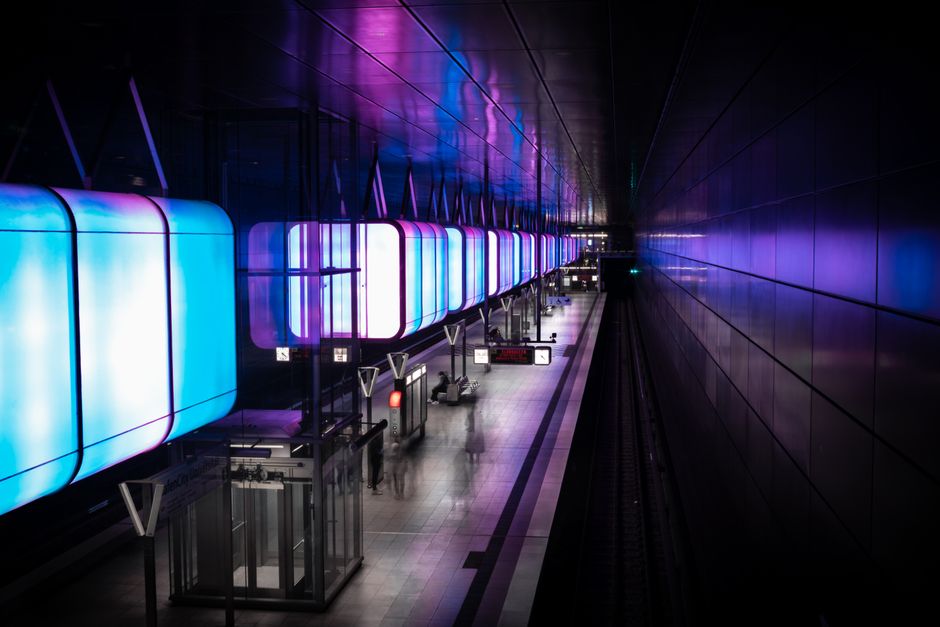 A vibrant view of an illuminated subway station platform in Hamburg, Germany, featuring neon lights.