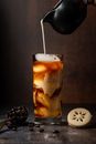 Milk Being Poured into Iced Coffee in Tall Glass on Dark Background