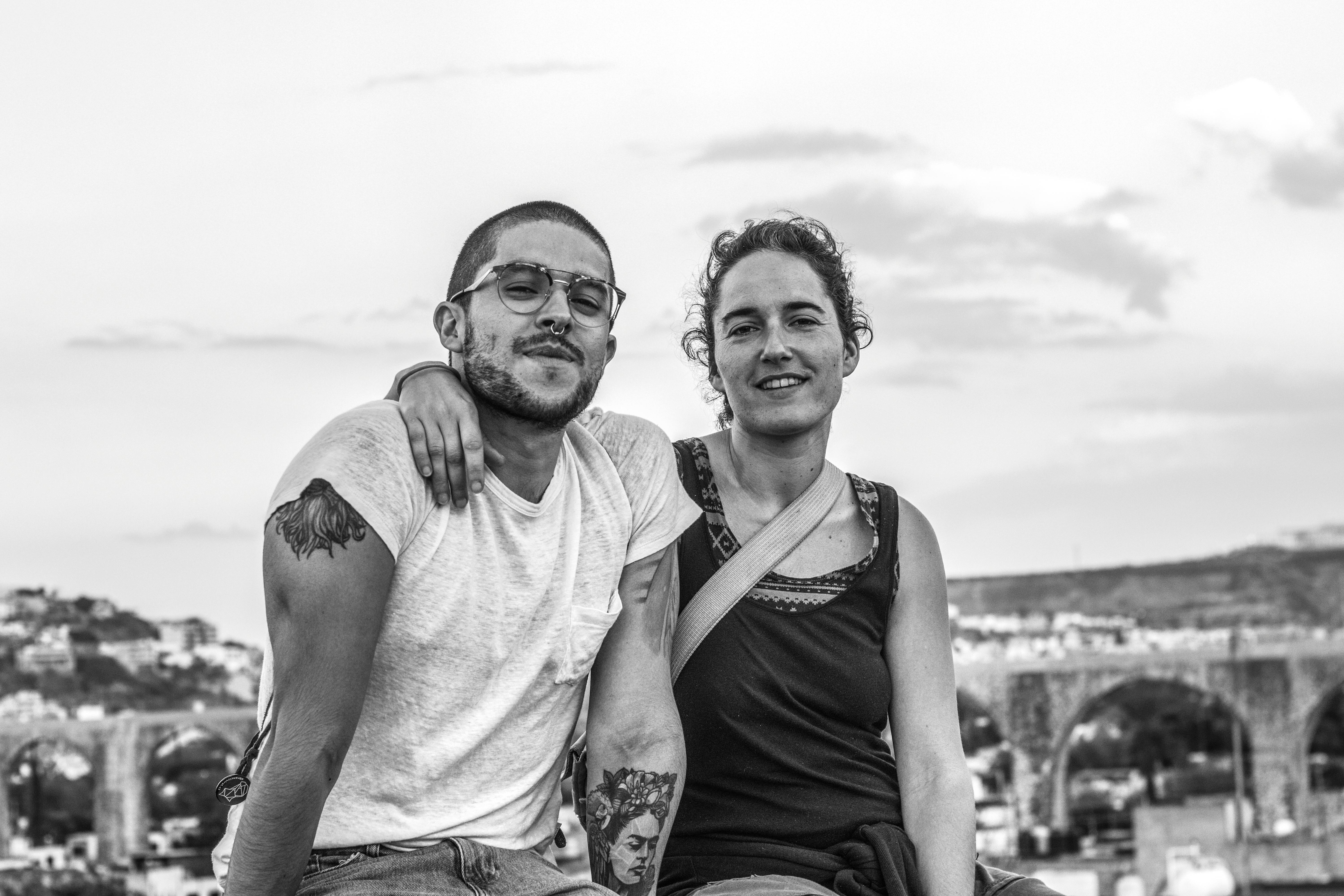 这幅黑白肖像描绘了一对悠闲的夫妇，他们正坐在户外，背景是风景如画的城市